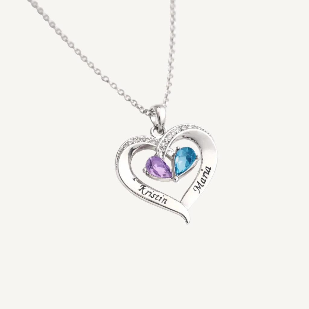 Silver heart-shaped necklace with two names engraved and two birthstones on a white background